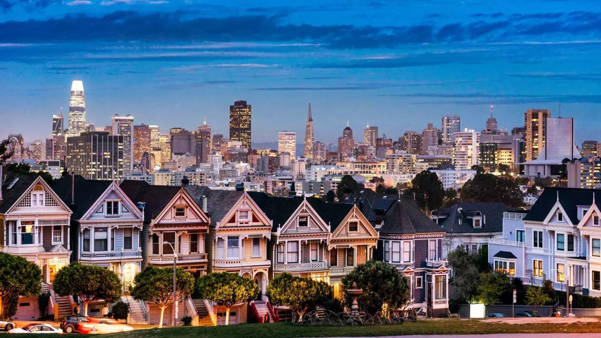 The famous 涂女士 of Alamo Square are pictured before the 贝博体彩app skyline at twilight.