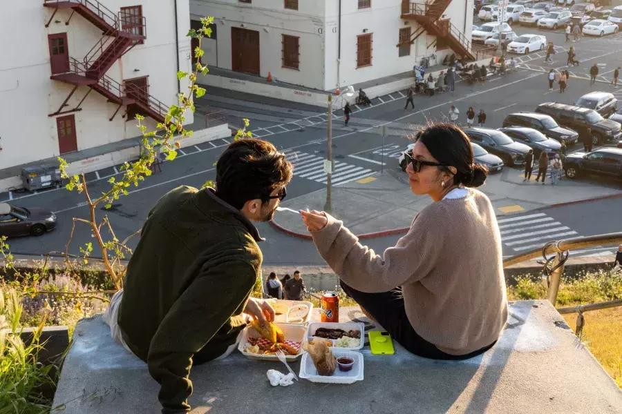 一对夫妇在贝博体彩app的梅森堡中心户外用餐. 女人用一口食物喂她的伴侣.