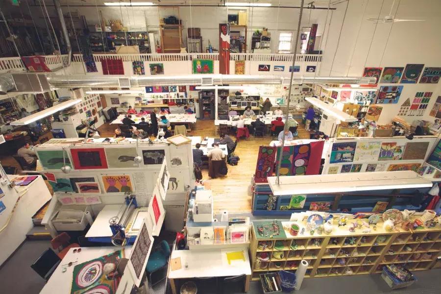 The floor of Creativity Explored, with an assortment of desks and works of art, seen from overhead.