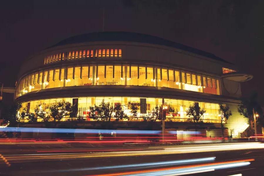 Außenansicht der Louise M. Davies Symphony Hall bei Nacht mit Lichtstreifen vorbeifahrender Fahrzeuge.