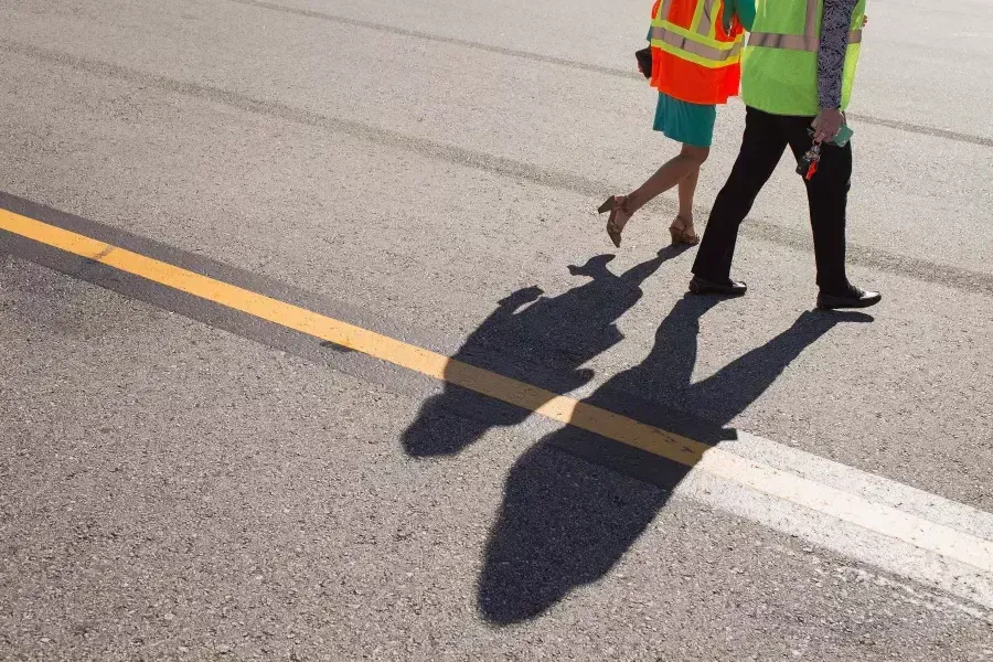 People walking with shadows on a runway.
