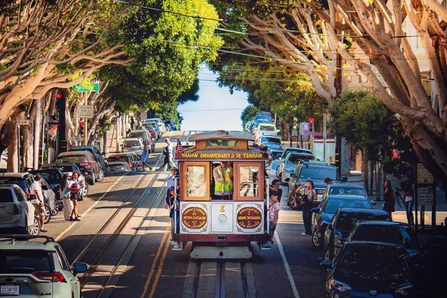 Auf einer von Bäumen gesäumten Straße nähert sich eine Seilbahn in San Francisco.
