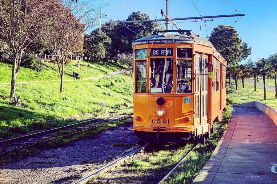 Die historische, orangefarbene Straßenbahn der F-Linie rollt eine Strecke im Stadtteil Castro in San Francisco entlang.