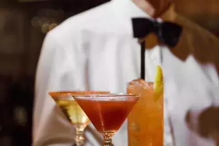 Ein Kellner mit Fliege präsentiert im Absinthe Restaurant in San Francisco ein Tablett mit Cocktails.
