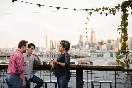 三个人聚集在贝博体彩app锚酒厂屋顶上的户外桌旁, California.