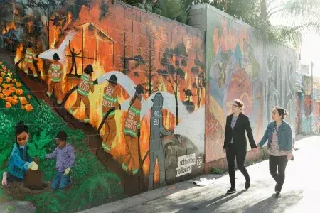 A female couple walk past a San Francisco mural.