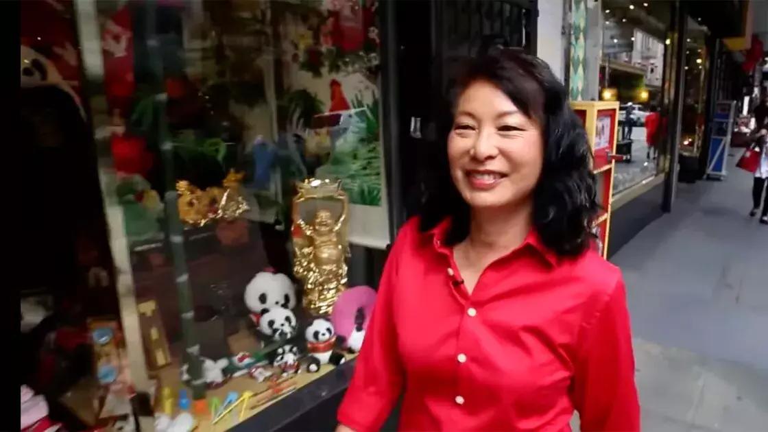 琳达·李穿着红色衬衫走在唐人街的街道上. 贝博体彩app，加州.